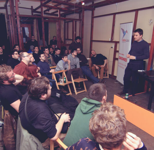 A speaker demonstrating technology to an audience in a wood-framed room