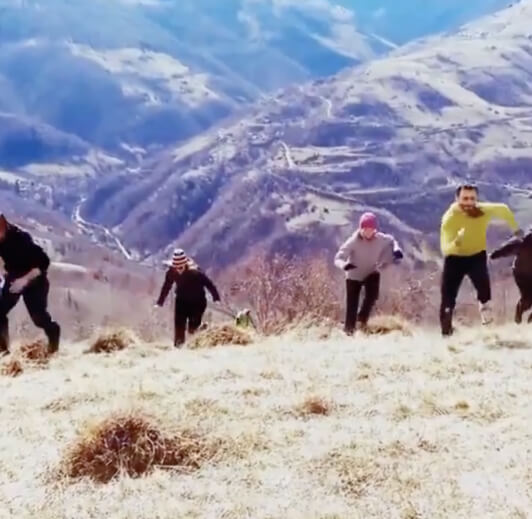 A small group moving up a grassy mountainside